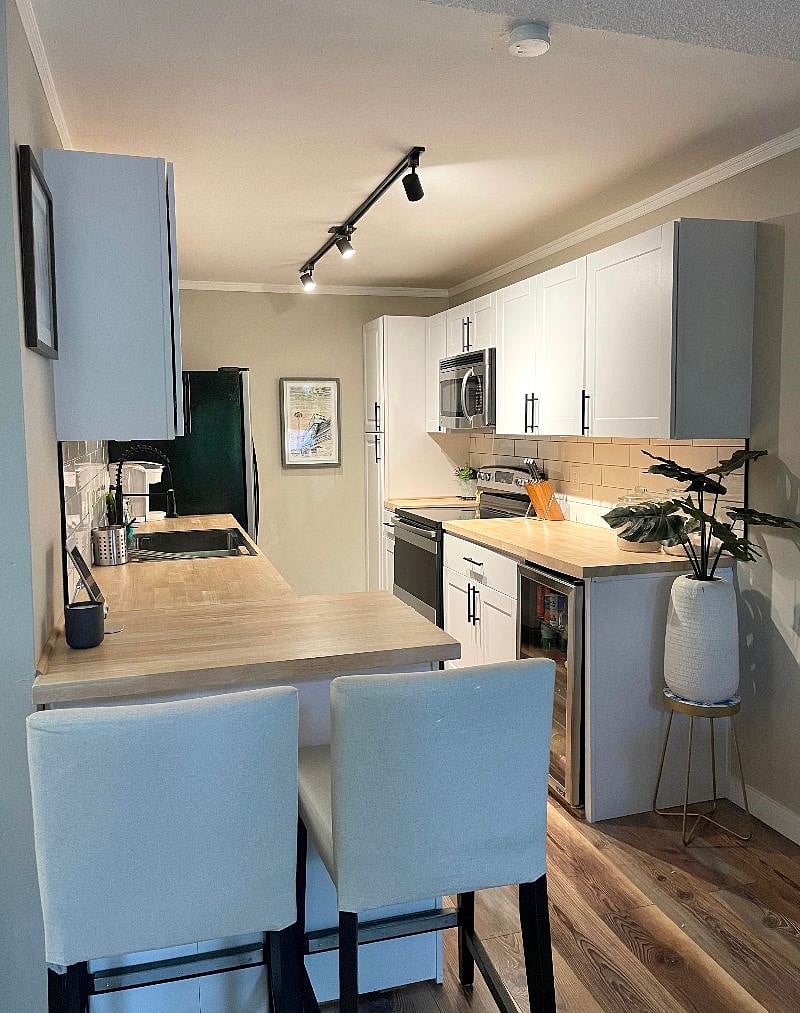 Updated kitchen with butcher block counter tops, stainless steel appliances, and a breakfast bar.