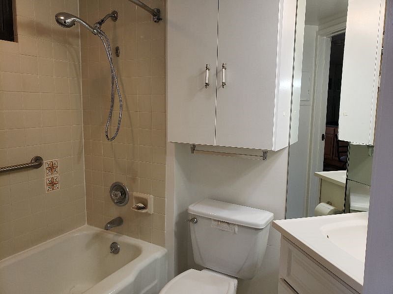 Bathroom with full tub and handle bars.