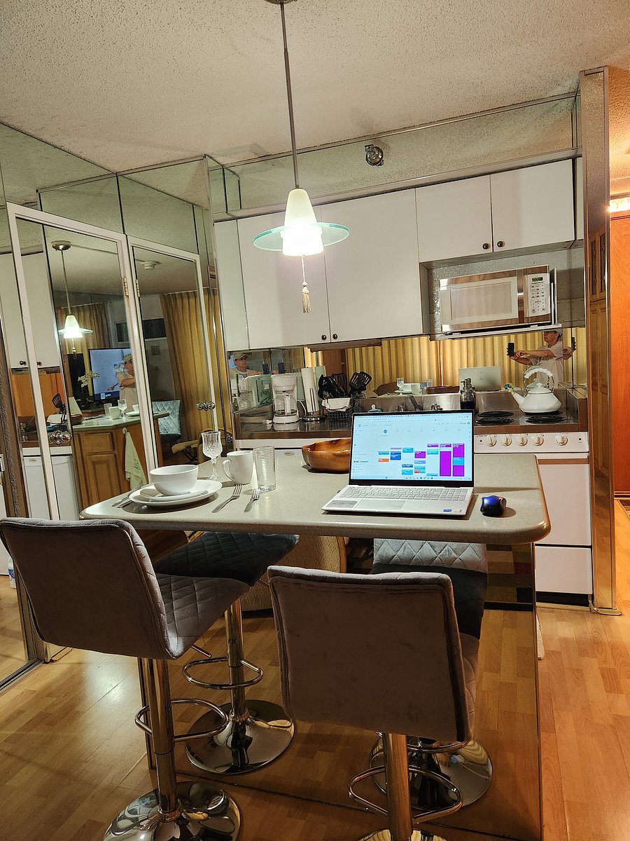 Living room perspective of the kitchen island, kitchen counter with stove/oven/microwave, hidden storage closet and bathroom.