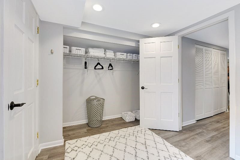 Large clean and fresh closet with organizer system plus lots of hangers and baskets for all of your storage needs.