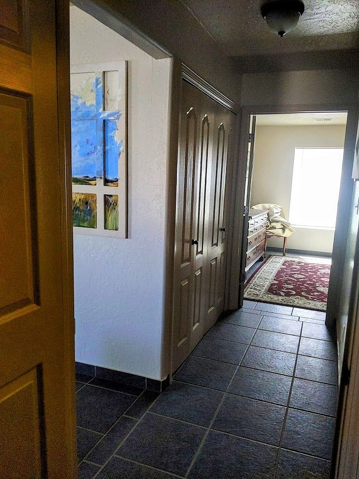 double french doors house washer and dryer adjacent to bathroom. The area has overhead cabinets for storage.