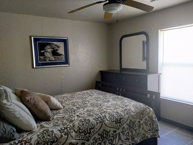 2nd bedroom triple dresser, queen bed, night stand table and lamp.