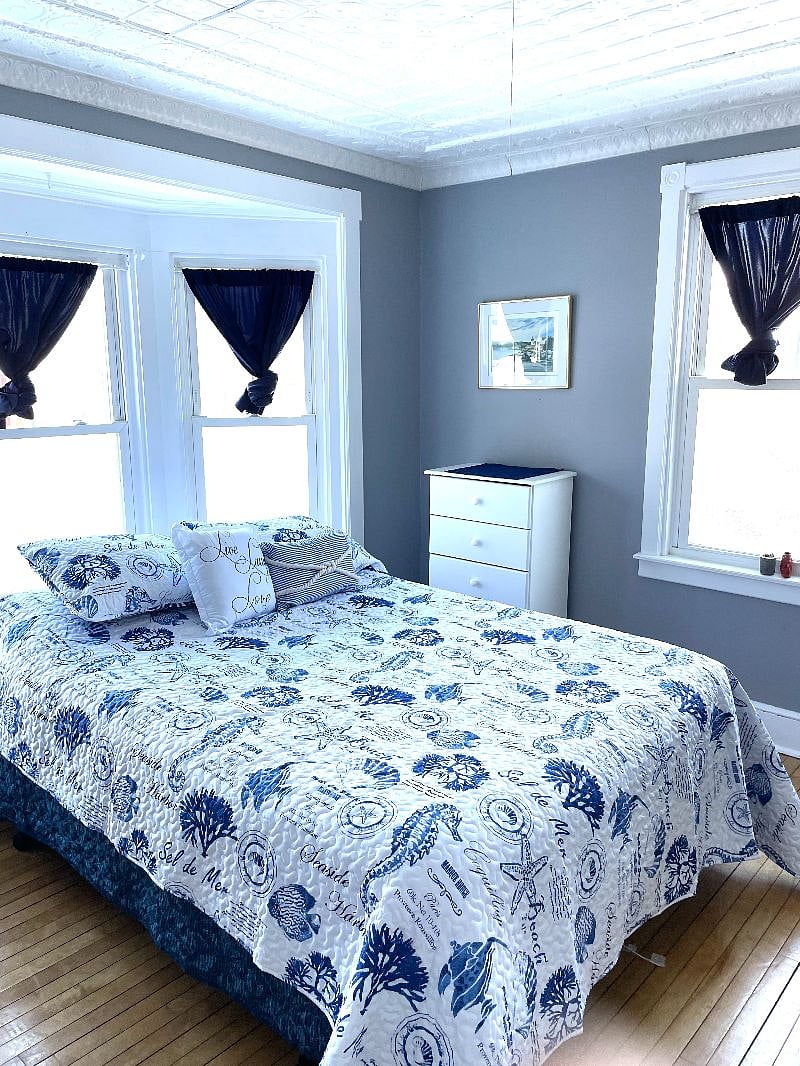 Bedroom #2. Queen size bed, night stand, lamp, dresser and closet. Tinted windows with dark out curtains. Bedroom #2 has hard wood floors , tin ceiling, a bay window and a side window.