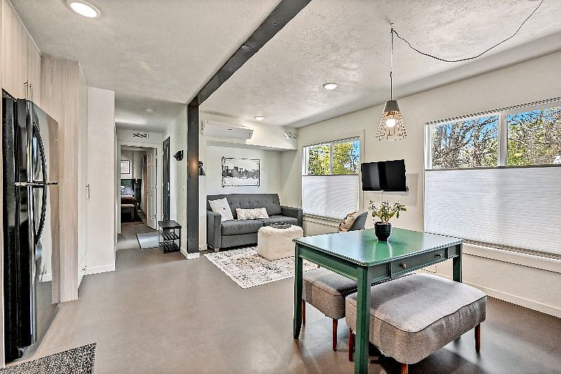 This is the main living space of our container home. Along the back wall is our kitchen, and in the open area we have provided a dining table, couch, and Smart TV.