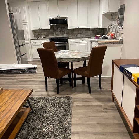 Looking from the living room into the kitchen, which has a new fridge, new dishwasher, new microwave, and new countertop and flooring.