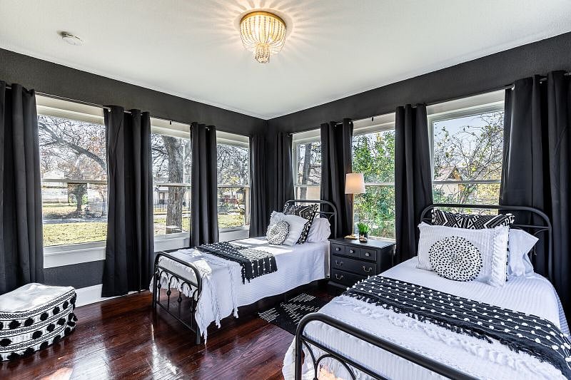 The third bedroom is framed by windows on three of the four walls. It has two twin beds, a nightstand and ottoman.