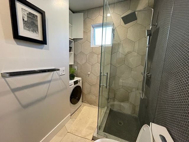 The combo washer-dryer is in the corner of the bathroom, with storage above.