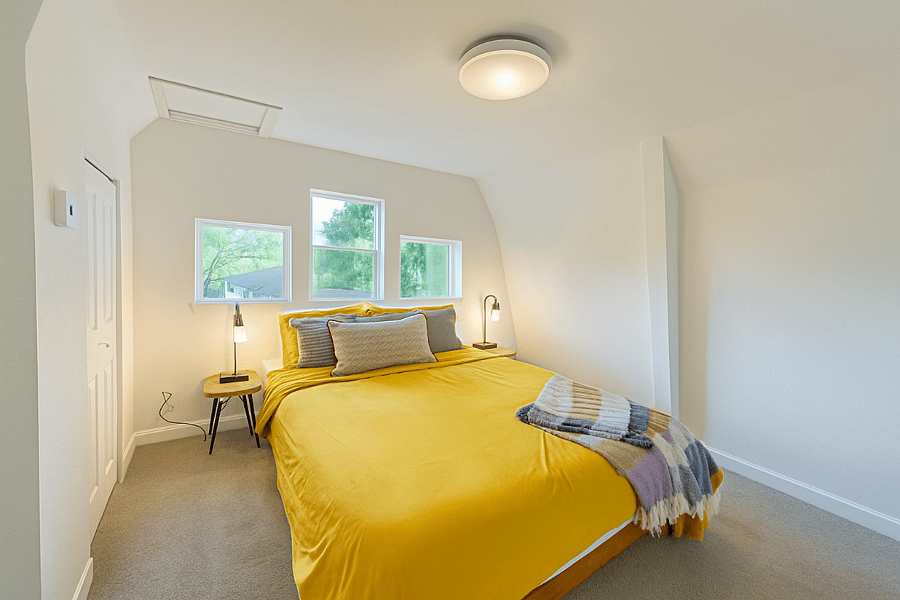 Wake up to lush treetop views from this vibrant bedroom featuring a cloud-soft queen bed and playful pops of yellow. A bright, cheerful space to start and end your day