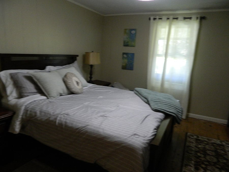 This middle room has a queen size bed and a smart tv .