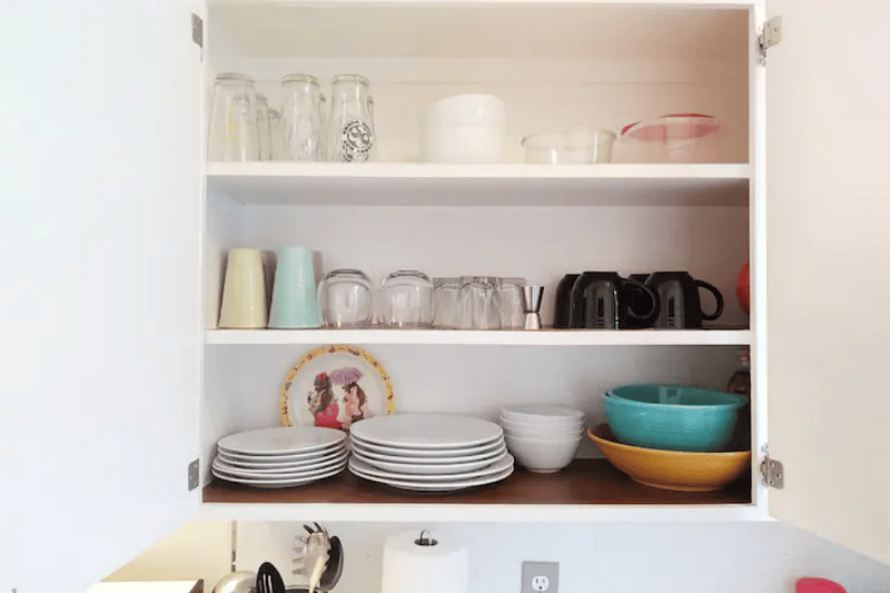 Kitchen is stocked with plenty of dishes, cutlery, utensils and cookware.