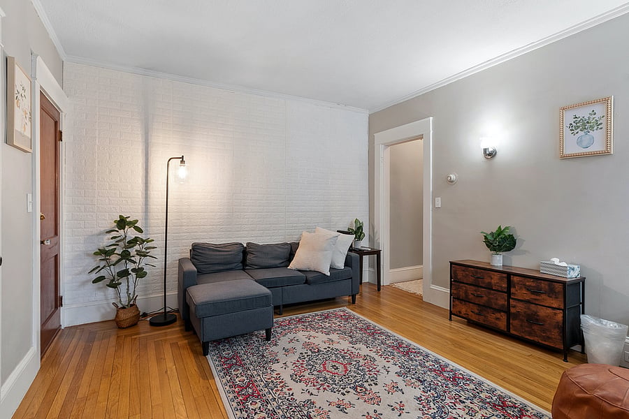 Relax in a bright, comfortable living room with a cozy couch, accent chair, bar cart, and TV. Perfect for unwinding, catching your favorite shows, or enjoying a quiet night in.