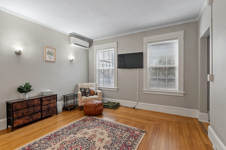 Spacious first-floor living area featuring a comfortable couch, accent chair, bar cart, and TV. Ideal for relaxing, entertaining, or enjoying downtime after exploring the neighborhood