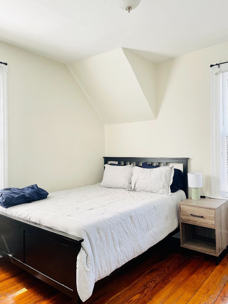 Bedroom 3 with queen-sized bed, desk & chair, clothing rack, and blackout curtains