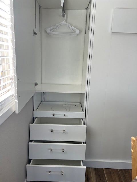Small closet and drawers next to bed. Top shelf rolls out with electrical outlet.