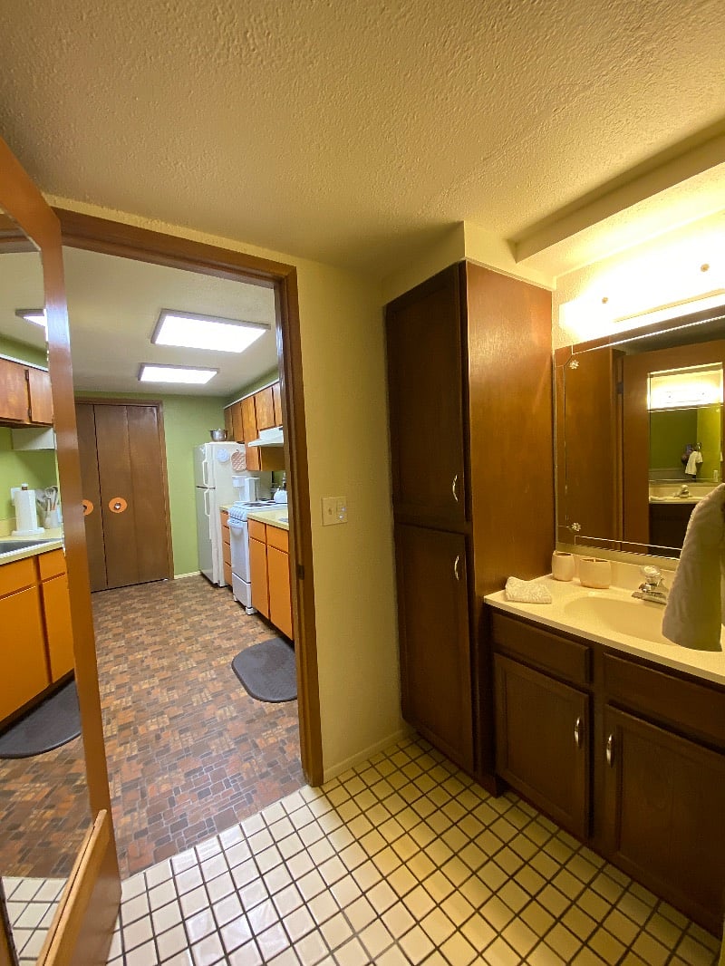 View from bathroom into kitchen. Full length mirror on bathroom door.