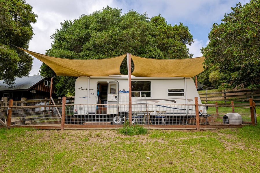 There is a fully fenced yard around the trailer. The trailer is surrounded by a pasture with chickens.