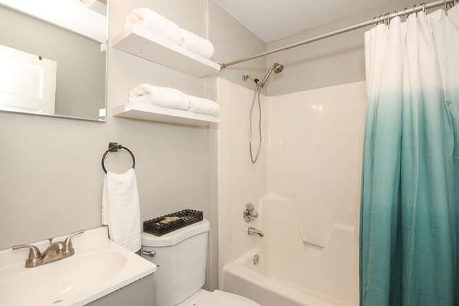 Clean bathroom with tub/shower combo and fresh towels
