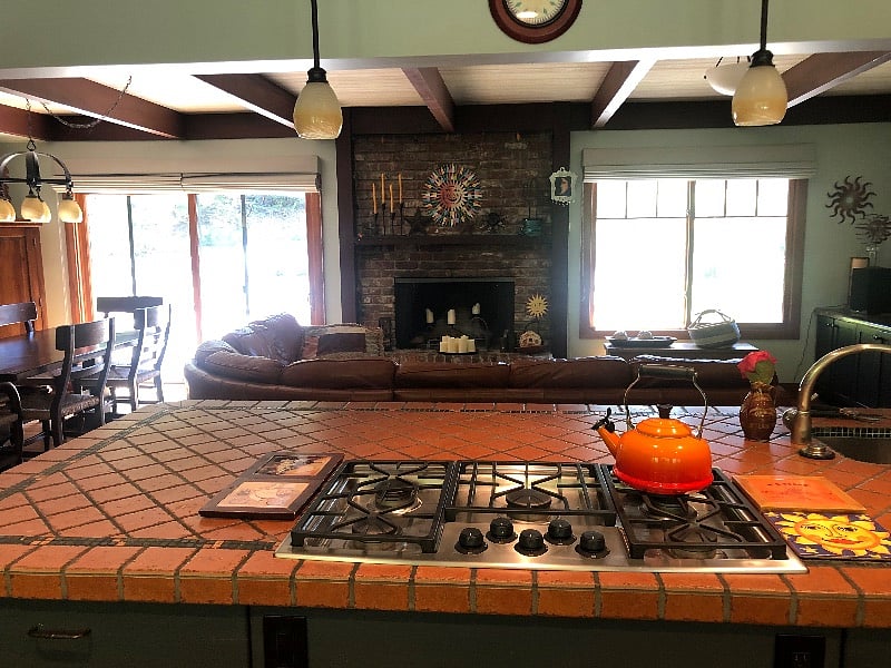 gas cooktop on large island facing fireplace and sliding door to backard.