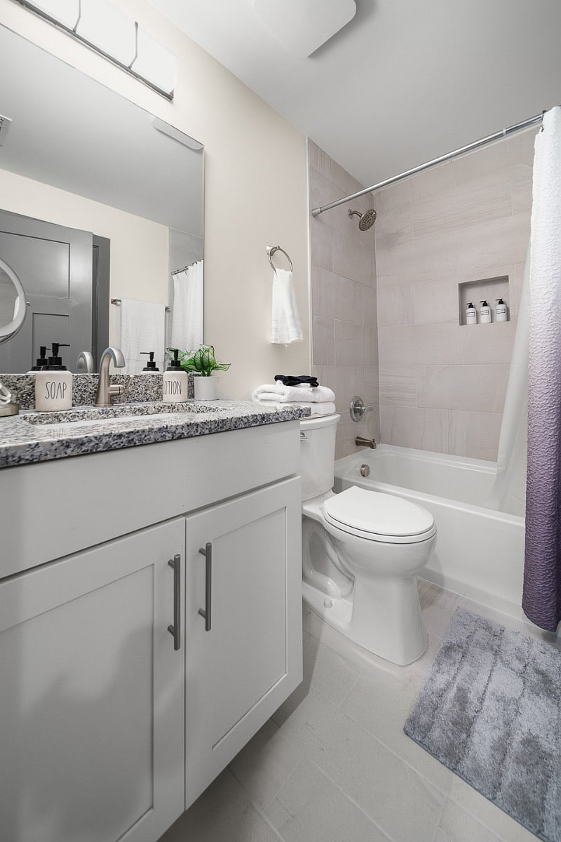 Bathroom in the unit stocked with makeup mirror, hair dryer and towels. This bathroom has two doors, one leading to the bedroom and one to the hallway leading to the living room.