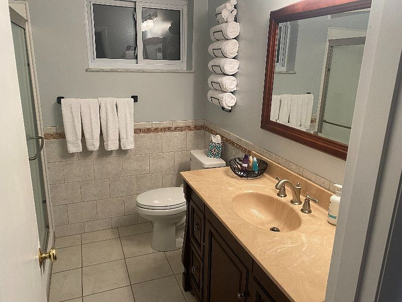 SECOND FULL BATHROOM FULLY REMODELED WITH NEWER VANITY, COMMODE, TILED FLOORING AND WAINSCOTTING WITH STAND UP SHOWER