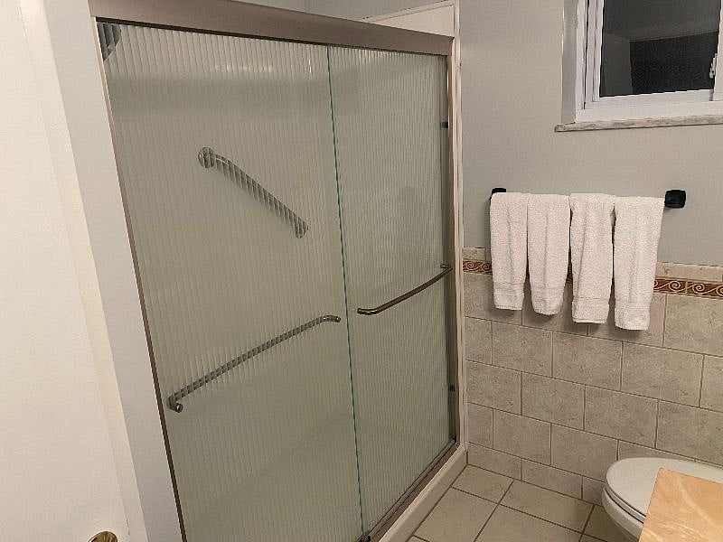 SECOND FULL BATHROOM FULLY REMODELED WITH NEWER VANITY, COMMODE, TILED FLOORING AND WAINSCOTTING WITH STAND UP SHOWER