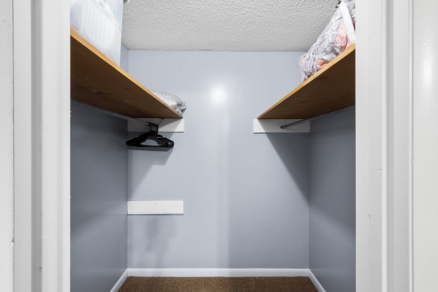 Master walk-in closet for bedroom with gray comforter