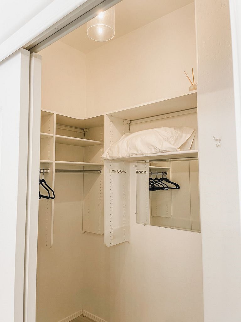 Walk-in primary bedroom closet with storage, hangers and hooks.