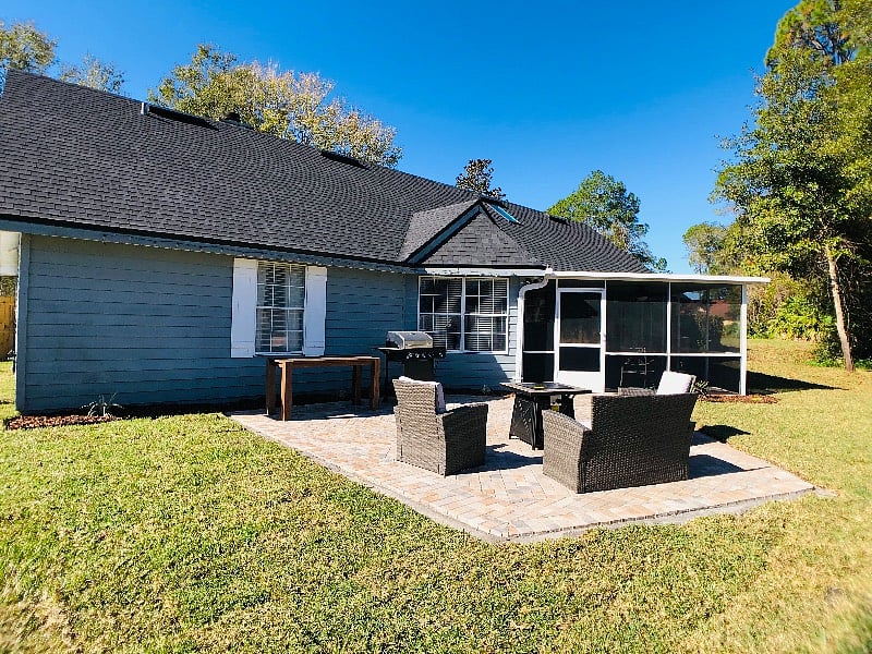 Rear exterior of home with screened patio, grilling area, and private yard