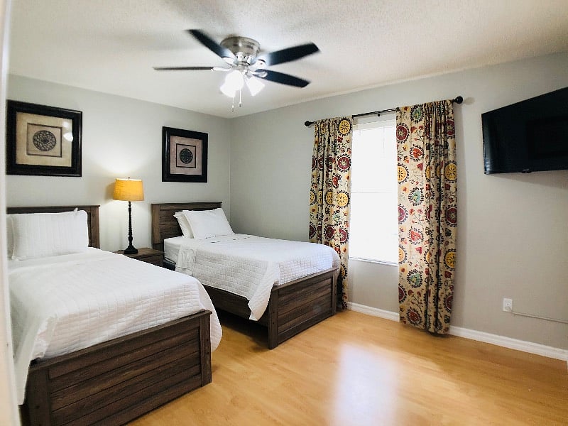 Third bedroom with two twin beds, Smart TV, and ceiling fan