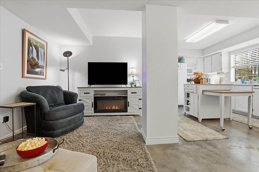 Stained concrete floors and lots of carpets Nice open great room style with TV stand with Electric fireplace for heat and winter ambiance!