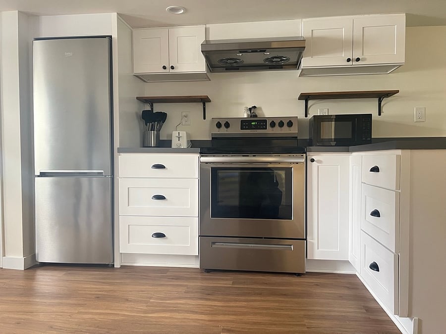 Kitchen has full sized oven and stove and is stocked with pots, pans, dishes and utensils.