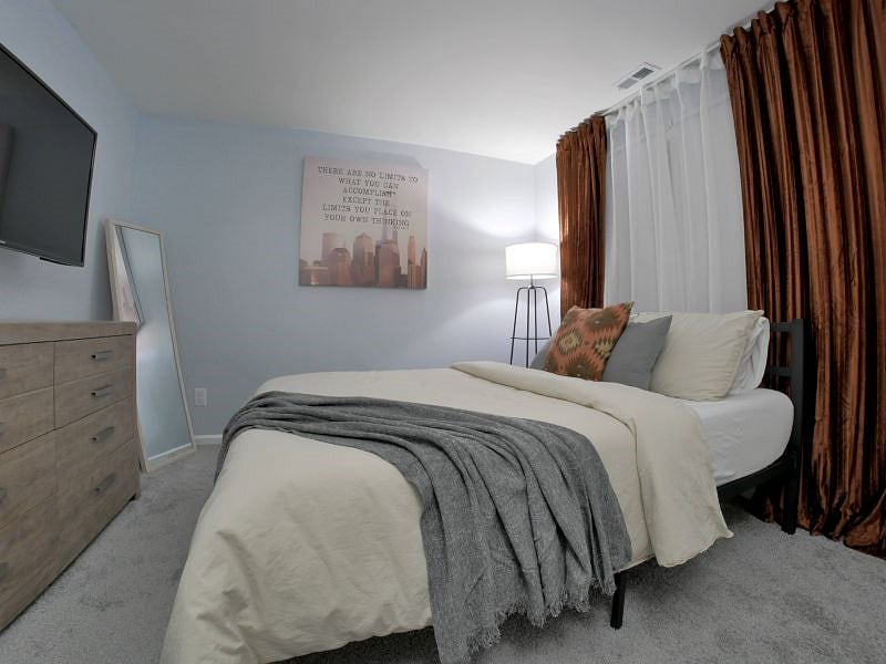 Bedroom 1. Features a 50" 4K LCD smart tv, full body mirror, and a chest of drawers with 3 large slide out drawers.