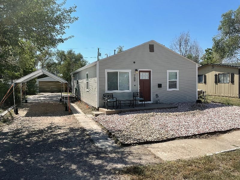 Front of house with new landscaping and carport.