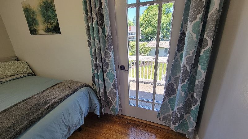 Room C: Twin adjustable bed, smart TV, and door leading to Private Balcony