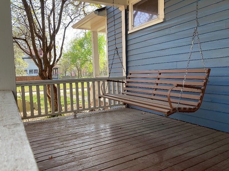 Swing on back porch overlooks the fenced back yard