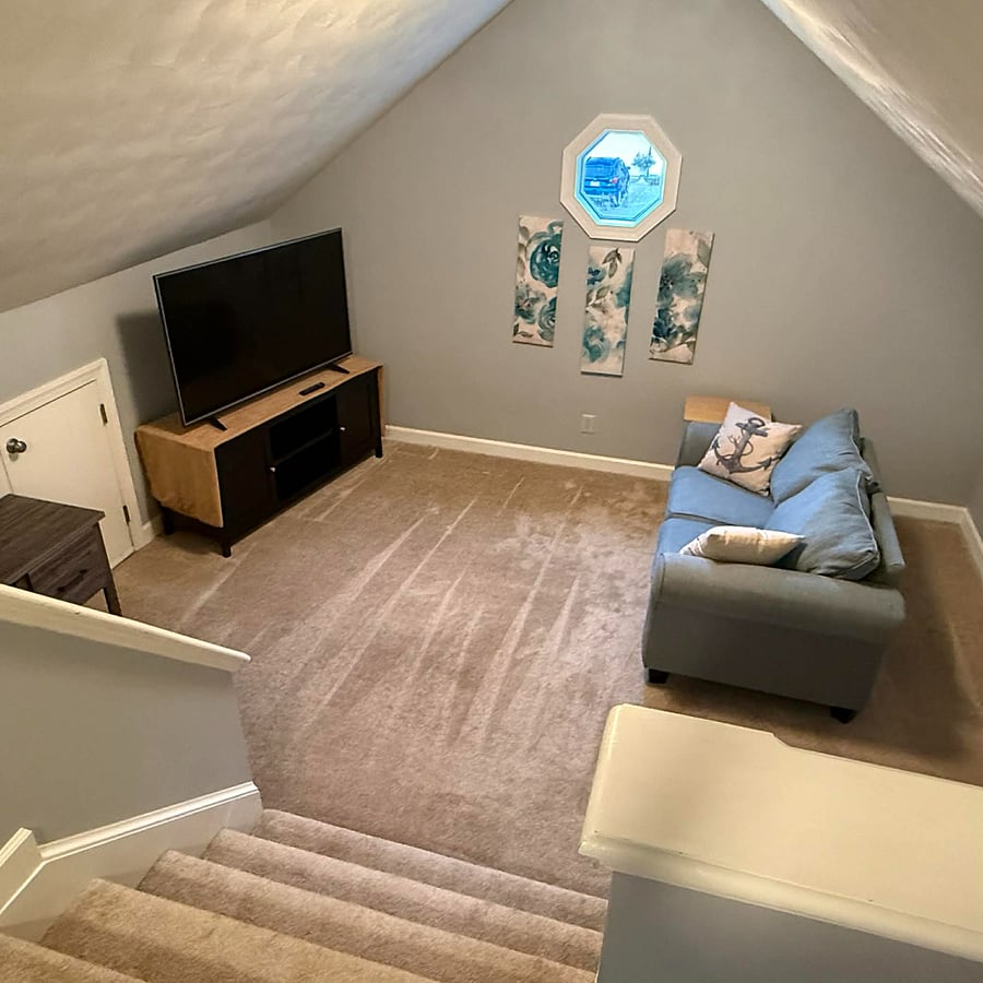 stairs down to lower level with sitting area, TV, and desk