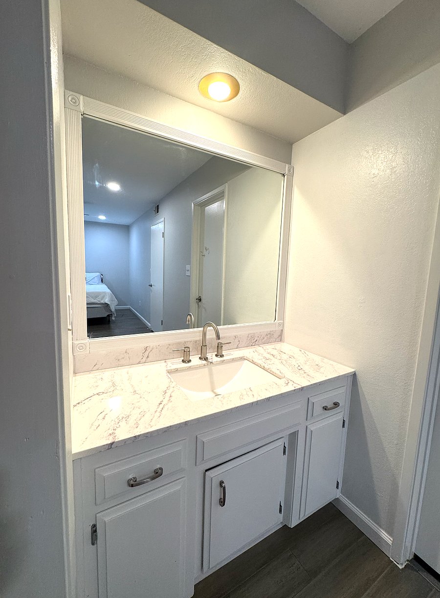 The master bedroom has an in-suite vanity with sink and mirror.
