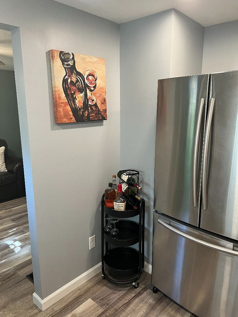 Bar cart stocked with wine holder, wine glasses, & whiskey glasses. Fridge has an automatic icemaker.