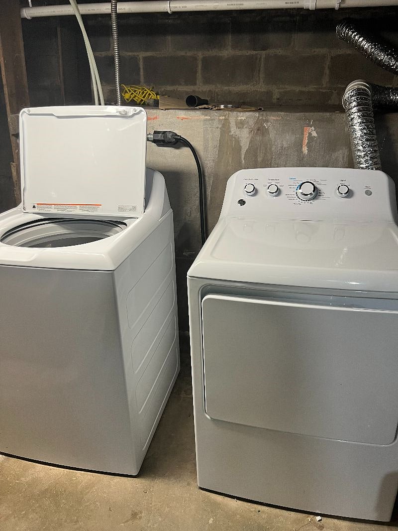 New washer and dryer in basement with additional storage space.