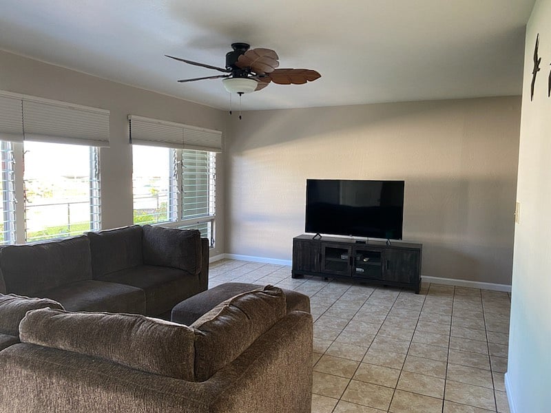 Living room furnished with l-shaped sofa and tv.