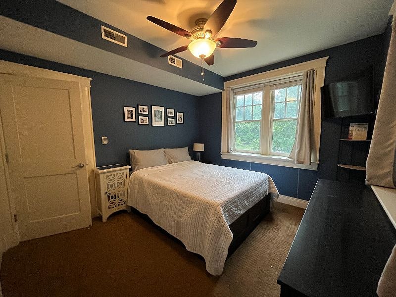 Primary bedroom with queen bed, dresser, large custom closet, and TV.
