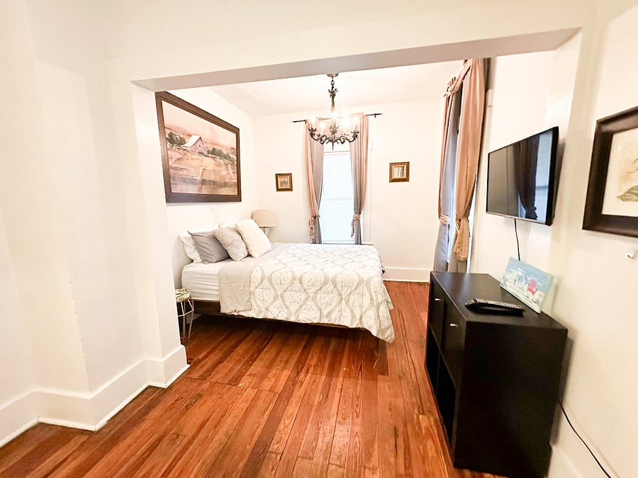 Bedroom 1 with TV, black-out curtains, ceiling fan & chandelier