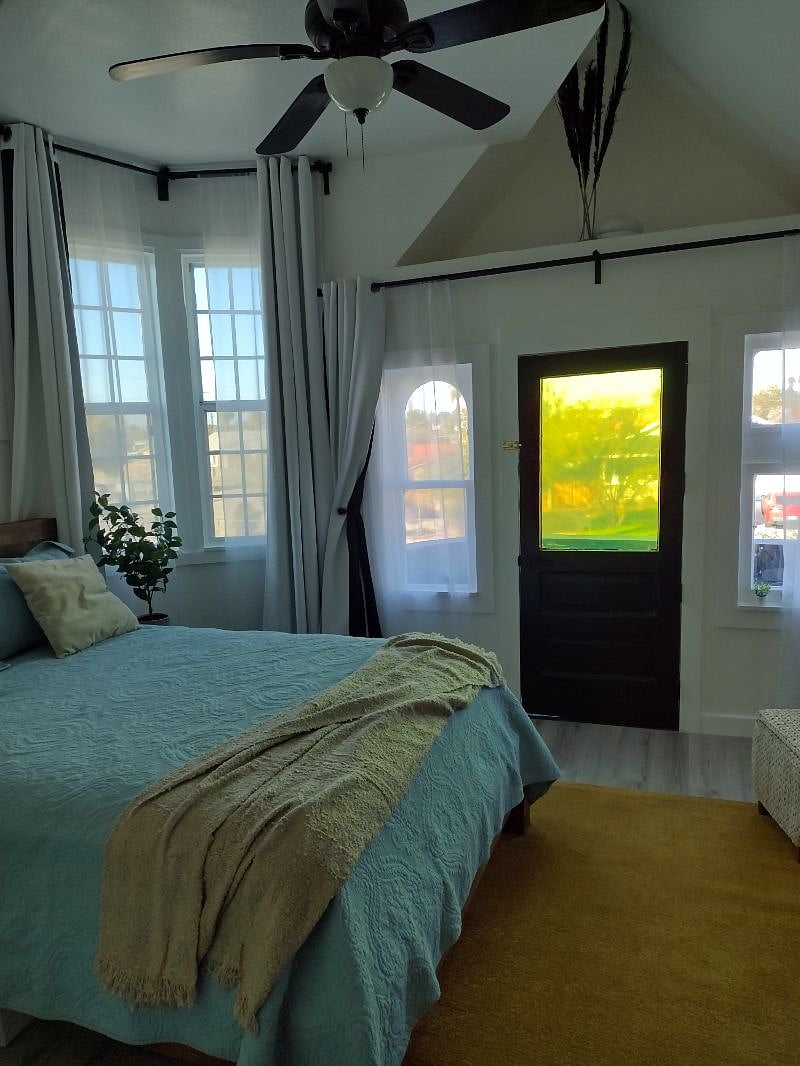 Beautiful bedroom with lots of windows and black out curtains and balcony off front of house