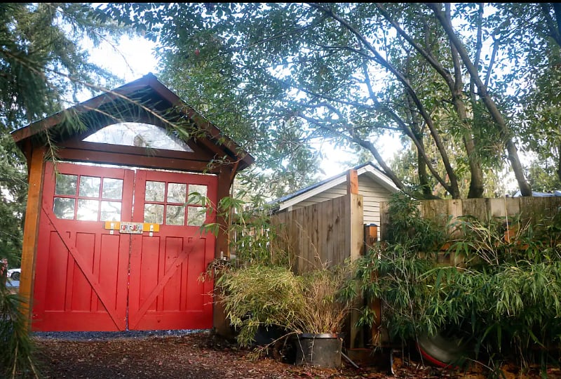 Entrance through iron gate next to red carriage doors.
