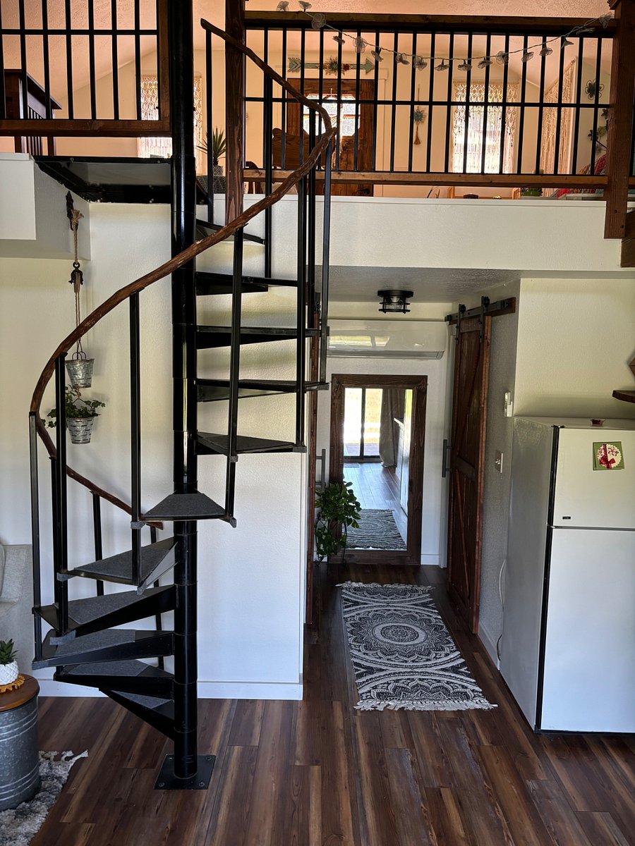 Spiral stairs lead up to an open loft bedroom, sitting, office area.