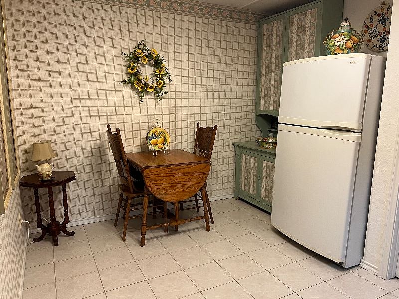 Kitchen with full refrigerator, microwave, cabinet, expandable table and two chairs.