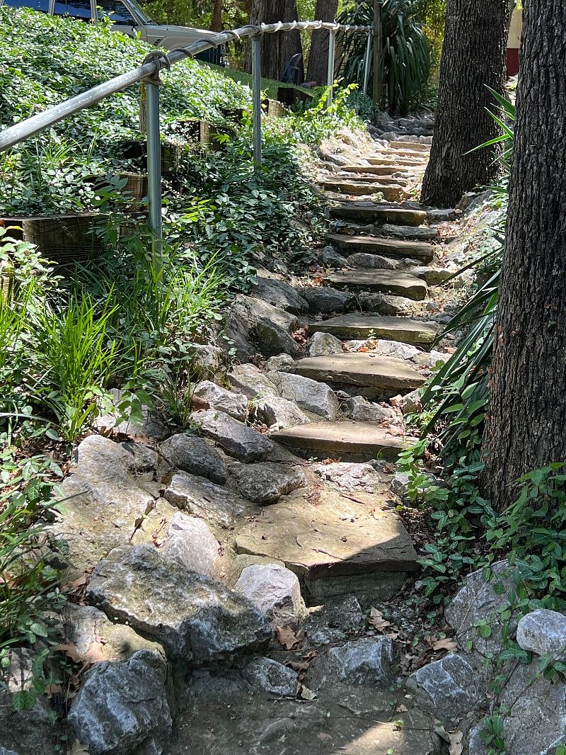 Stone stairway to apartment entrance with handrail.