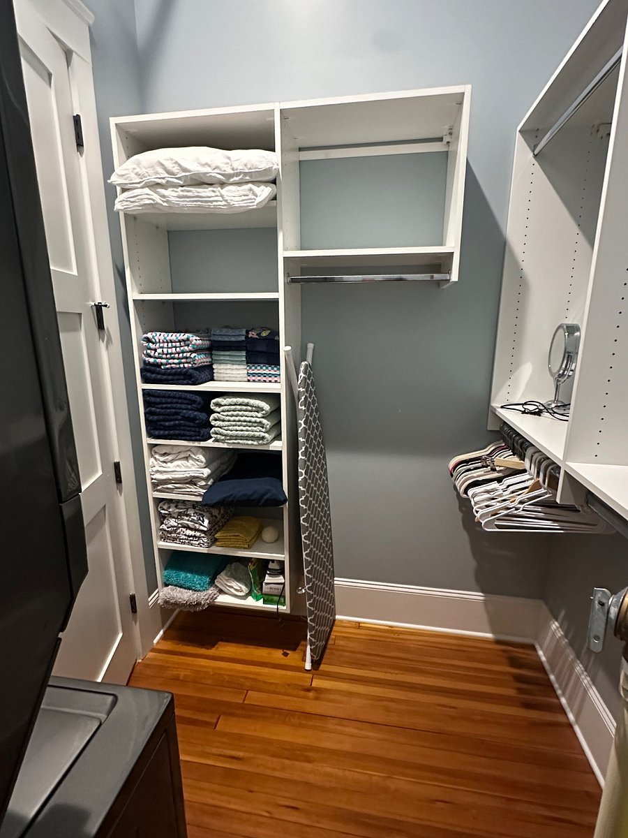 Primary closet with towels, linens, iron and ironing board