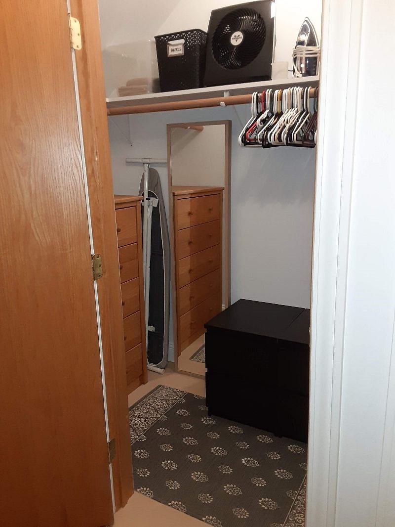 Large closet with dresser, hangers, iron, ironing board, fan, full-length mirror, hamper, sewing basket