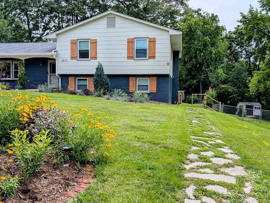 Front of house. Walkway around to back for tenant entrance. Tenant quarters are lower half, with many windows.